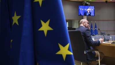 Europeiska rådets ordförande Charles Michel. Bilden domineras av en stor EU-flagga i förgrunden. I bakgrunden syns en videoskärm.