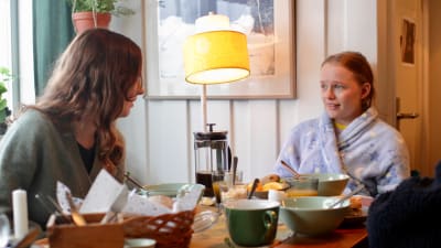 Madde och Ida tittar på varandra vid frukostbordet.