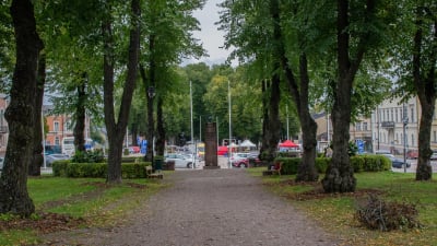 Monumentparken i Lovisa. På bilden syns ett esplanadområde, med en grusväg i mitten kantad av stora lövträd. I ändan syns ett monument i sten. 