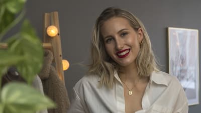 En blond kvinna iklädd vit skjorta. Hon ler. 