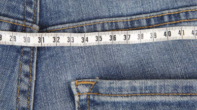 Närbild på ett par jeans med måttband ovanpå (illustrationsbild för övervikt).