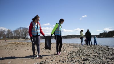 ungdomar plockar skräp på en strand