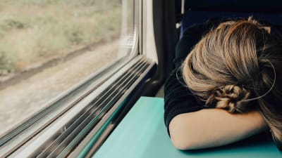 Väsynyt nainen junassa.