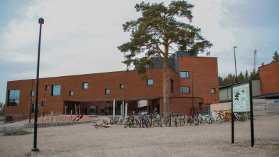 Röd skolbyggnad i tegel med cyklar parkerade framför.