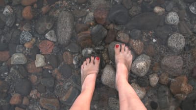 Fötter nedstuckna i det klara vattnet i Puruvesi.