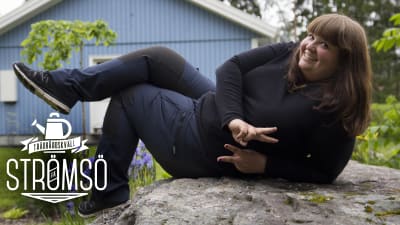 Kristine Vesterlund  poserar liggand epå en stor, grå sten. 