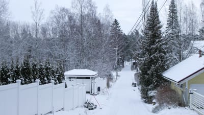 en snöig väg, staket och hus och skog kring den smala vägen
