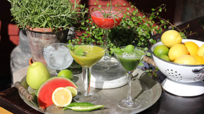 Tre drinkar i cocktailglas. Två gröna och en röd.