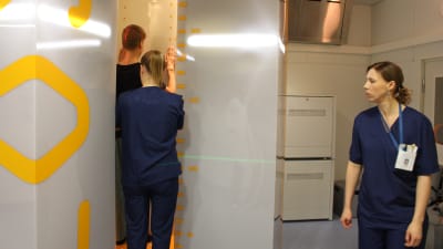 Patient står i ny röntgenapparat vid ÅUCS och får hjälp av två röntgenskötare. 