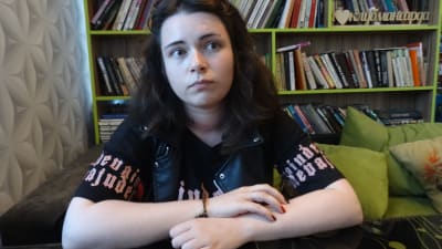 Alina Petrovitj är något så ovanligt som en rysk feminist. Här sitter hon med armarna i kors i en grön soffa framför en bokhylla.