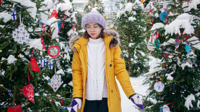 20-vuotias Saara Strum seisoo koristeltujen joulukuusten välissä Toivolan Vanhalla Pihalla Jyväskylässä ja katsoo maahan.