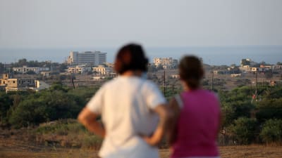 Två grekcyprioter från Varosha står på den cypriotiska sidan om gränsen och tittar på Varosha.