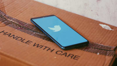 en mobiltelefon med twitters logo ligger på en låda med texten "handle with care"