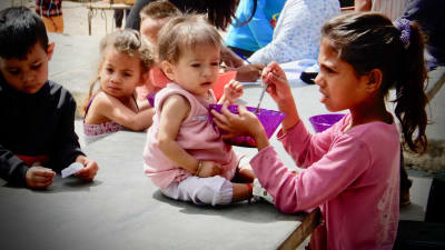 Lapsi ruokkii aliravittua pikkusisartaan Venezuelassa