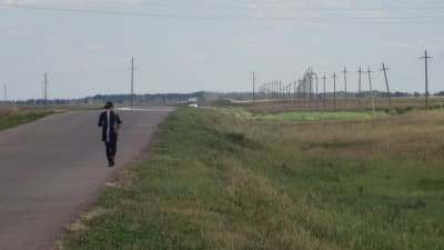 En kvinna går på en landsväg i Kazakstan.
