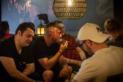 En grupp med killar sitter vid och röker joint.