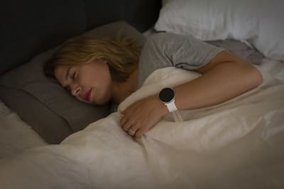 En person som sover med sportklocka i handen.