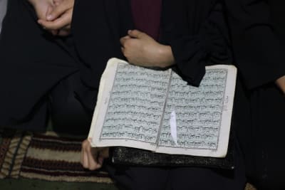 En Koran på arabiska, öppen i en flickas famn.