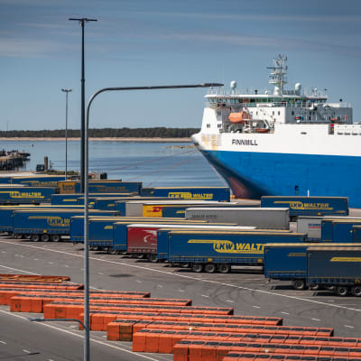 Containrar och ett lastfartyg i Hangö hamn en solig sommardag, folktomt på kajen.