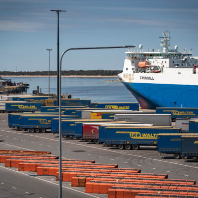 Containrar och ett lastfartyg i Hangö hamn en solig sommardag, folktomt på kajen.