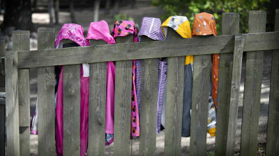 Barns regnrockar hänger på ett staket