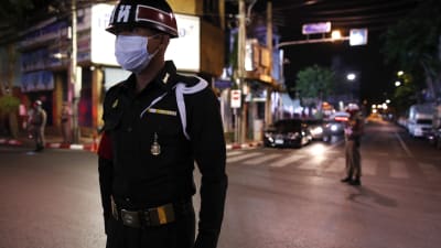 En polis i Bangkok övervakar det nattliga utegångsförbudet i staden