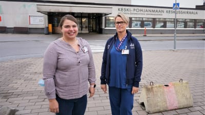 Två kvinnor står utanför en sjukhusbyggnad.