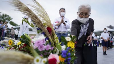 En äldre kvinna lägger blomma för att hedra de 210 000 dödsoffren i Hiroshima och Nagasaki.