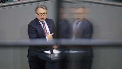 Den bayerske CSU-politikern Georg Nüsslein står och pratar och pekar i en talarstol. En suddig variant av honom speglas i en skärm.