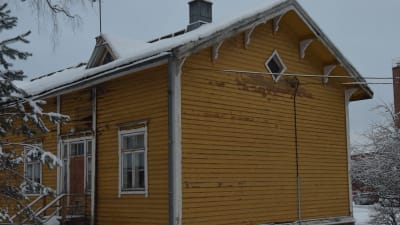 En gul trävilla, gammal arbetarbostad med fler bostäder. Målfärgen flagar, stockarna är ruttna vilket lett till hål i ytterväggarna.