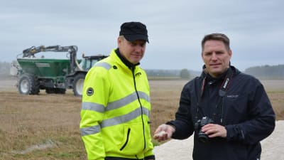 Juhs Ääri och Henri Vaarala står på en åker  - i bakgrunden en traktor.