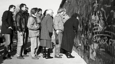 Människor tittar igenom ett hål i Berlinmuren 11.11.1989.