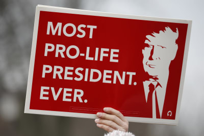 En person håller upp en skylt av Trump där det står "most pro life president ever".