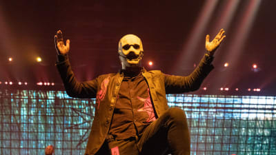 Slipknots sångare Corey Taylor iklädd en vit mask uppträder på scen.