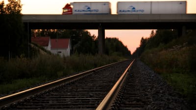 En långtradare susar förbi på en järnvägsbro.