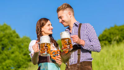 Tyskt par skålar med öl i folkdräkt. 