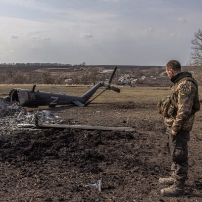 Ukrainalainen sotilas katselee alas ammutun venäläisen helikopterin romua. 