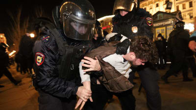 Tre poliser i kravallmundering håller fast en demonstrant i S:t Petersburg 27.2.