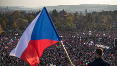 Man står med ryggen mot kameran och håller i tjeckisk flagga.