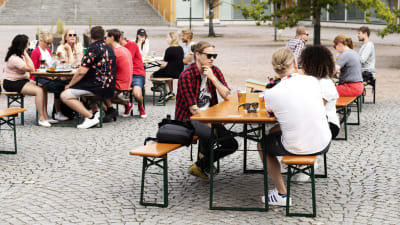 Människor sitter utomhus på en restaurangs uteservering. 