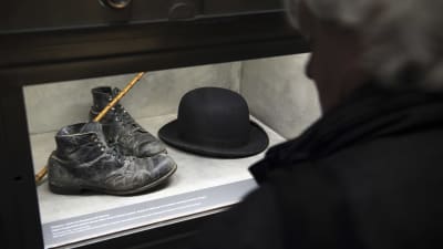 En besökare tittar på skoparet, plommonstopet samt promenadkäppen som tillhört Charlie Chaplins berömda luffar-karaktär.