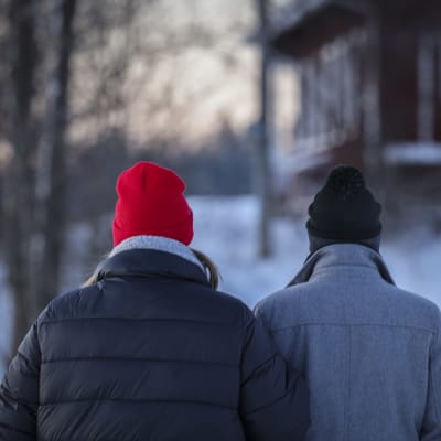 Nainen ja mies kävelevät käsikynkkään talvipakkasella.