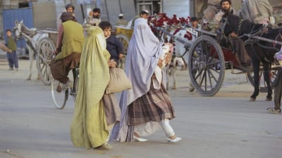 Kaksi naista Afganistanissa kävelee kantaen lasta sylissään..