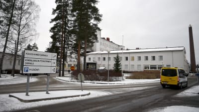 Norra Kymmenedalens sjukhus i Kouvola, en vit byggnad med träd i förgrunden. En ambulans kör förbi.