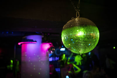 En discoboll lyser grön ovanför ett dansgolv.