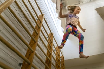 Flicka hoppar i en gymnastiksal.