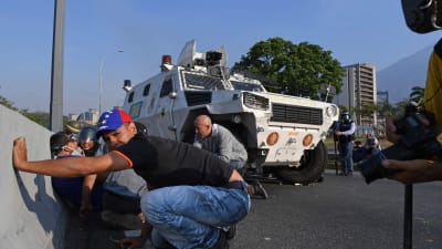 Människor söker skydd under en eldstrid mellan oppositionsanhängare och regeringstrogna soldater i Caracas