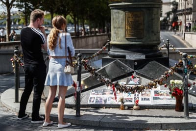 Två personer tittar på souvenirer som andra lämnat till minne av prinsessan Diana vid Frihetens flamma i Paris, alldeles intill tunneln där prinsessan dog i en våldsam bilkrock. 