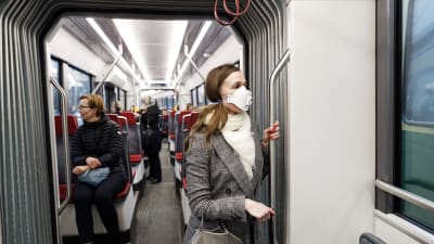 En kvinna bär munskydd i spårvagnen.