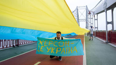  En ukrainsk flagga sträcks över en bro.